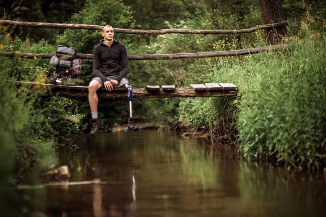 amputee hiker sitting on bridge over water accessible travel concept